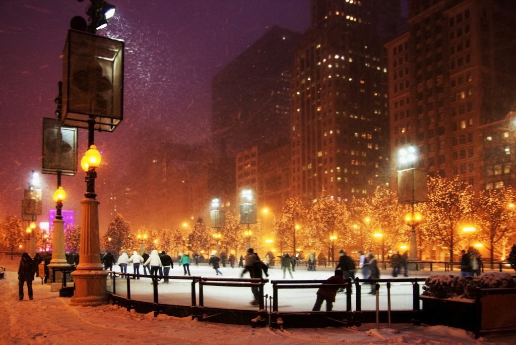 Winter night in Chicago. People enjoying ice skating at Millennium park ice rink during snowy night in Chicago.