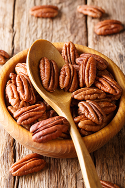 Raw pecan nuts in a bowl close-up. vertical